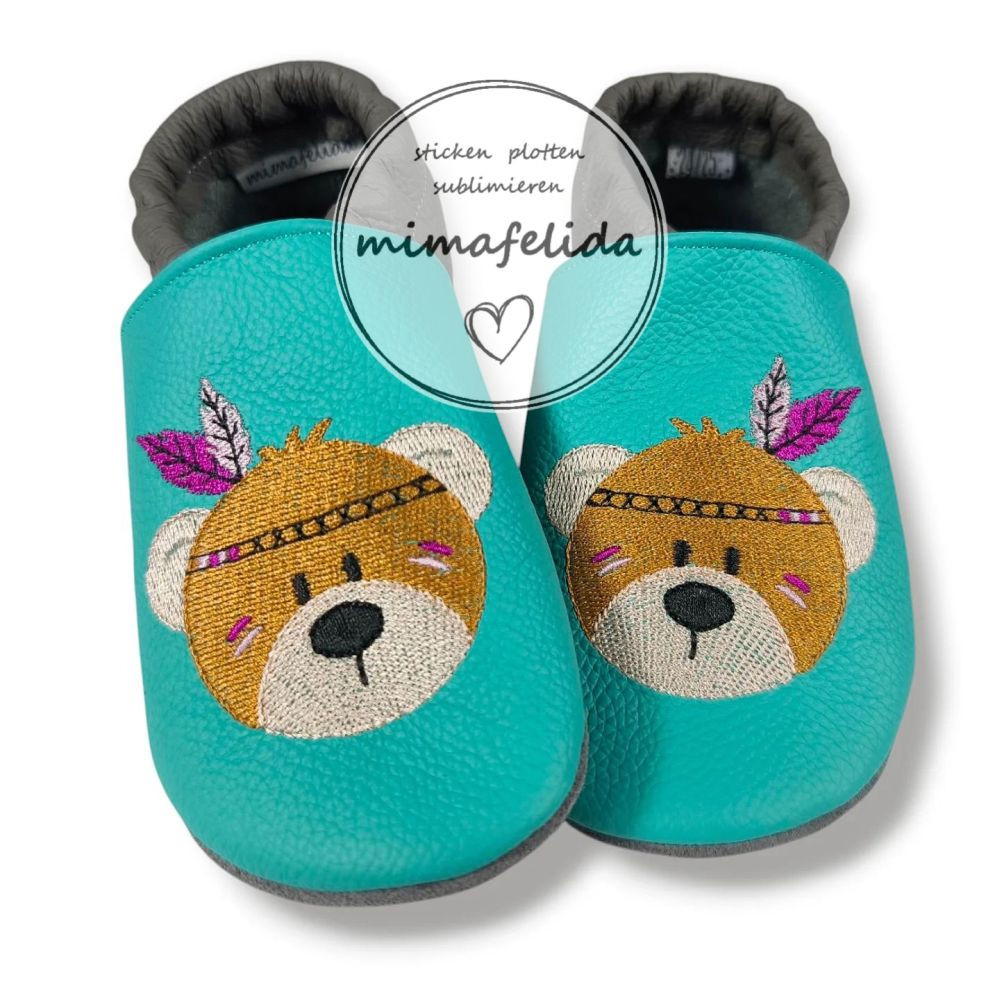 Lederpatschen mit einem Bärenkopf mit Federn bestickt