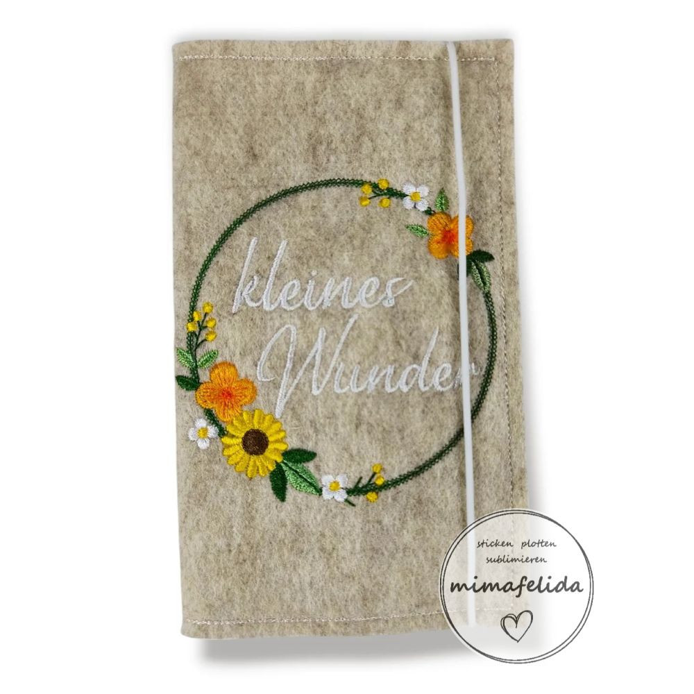 Mutterkindpasshülle mit einem Blumenrahmen und Text kleines Wunder bestickt